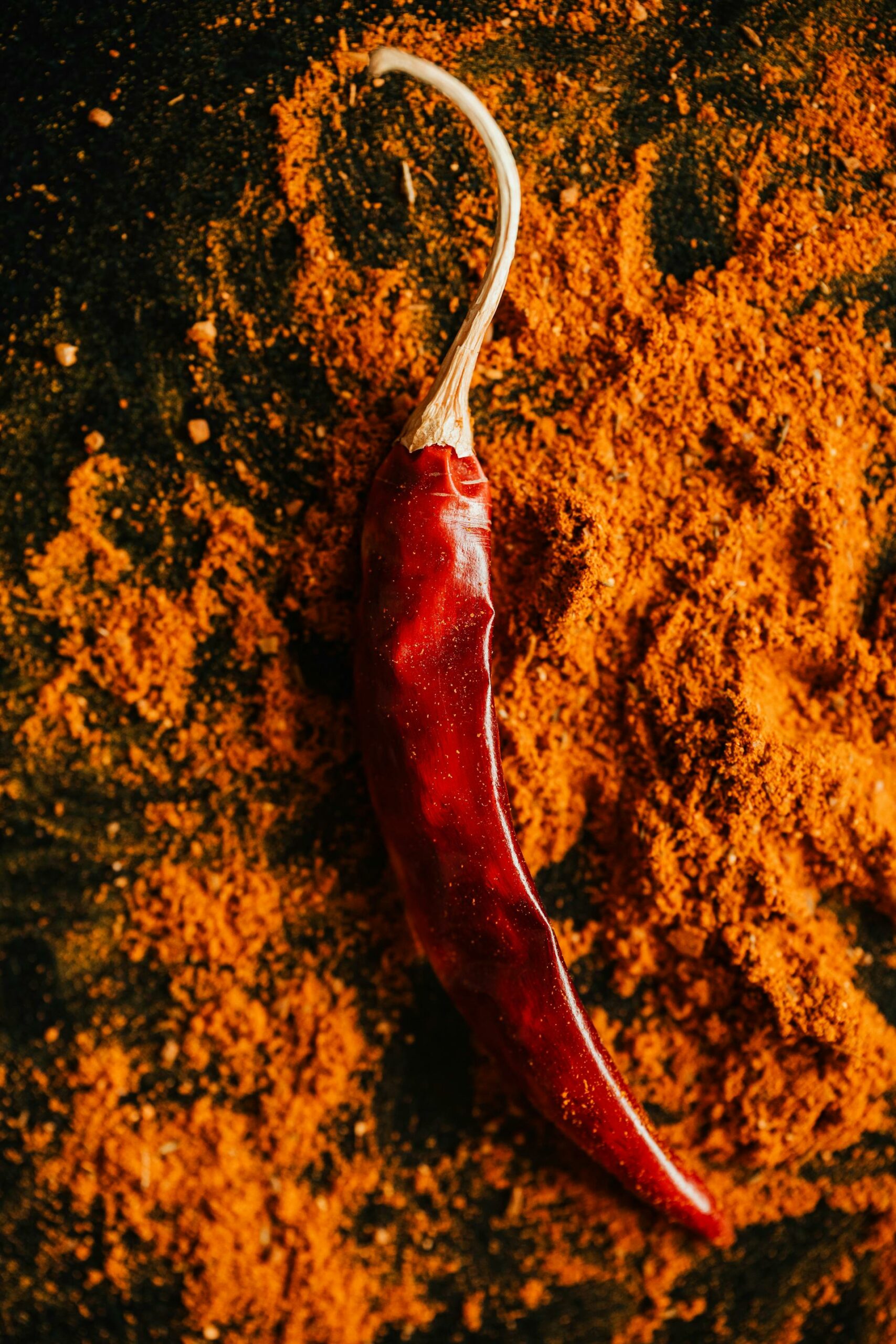 paprika powder with a fresh paprika pepper on top of it